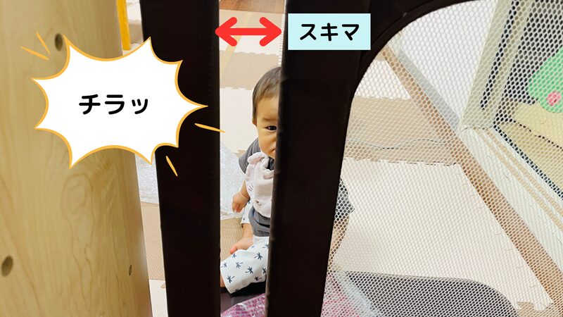 ベビーゲートの隙間越しに赤ちゃんと目が合っている写真です